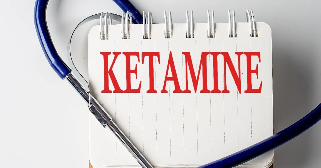 A stethoscope surrounding a notepad with the word “KETAMINE” written in bold red letters, representing medical use or treatment involving ketamine in Buford, GA